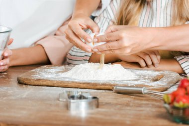 Kırpılan atış rustik masada hamur için un içine yumurta kırma kadın ve çocuk