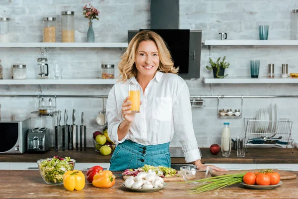 Prachtige Volwassen Vrouw Drinken Sinaasappelsap Tijdens Het Koken Keuken Camera — Stockfoto