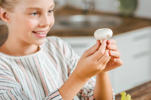 close-up shot of beautiful little child holding raw mushroom