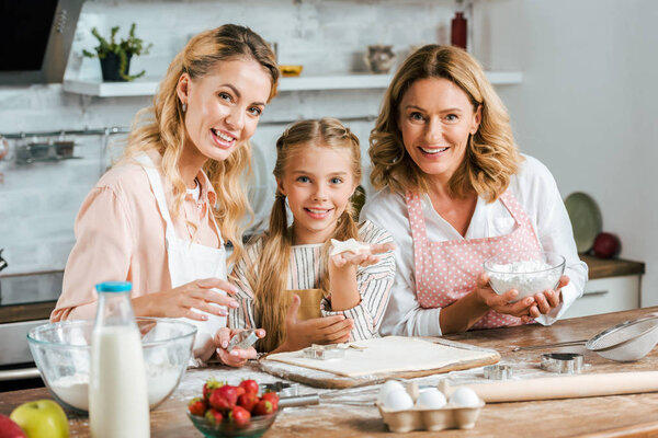 beautiful happy three generations of women making dough for cookies at home