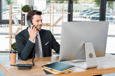 ofiste sabit telefonla konuşurken ve bilgisayar başında seyir yakışıklı işadamı gülümseyen