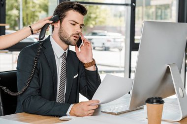 konuşmak Smartphone ve onu sabit telefon yakışıklı veren Sekreter tarafından işadamı