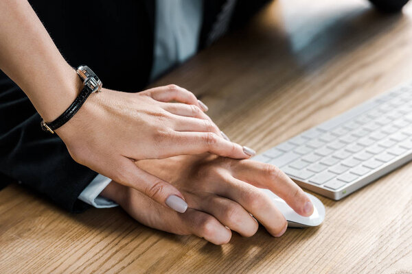 cropped shot of businesswoman holding colleagues hand while flirting