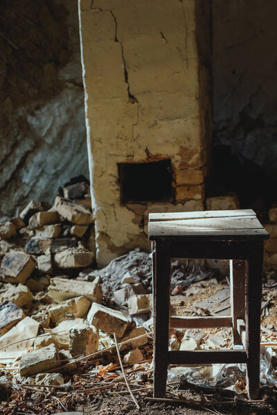 abandoned building with broken brick wall and wooden dirty chair