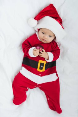Küçük Bebek beşiğinde yatan Noel biblo tutan Noel Baba kıyafetli üstten görünüm