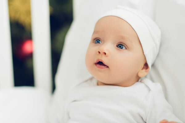 close-up portrait of adorable little baby in white hat looking away