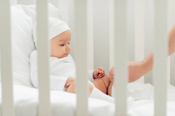 adorable little baby in white hat sitting in crib