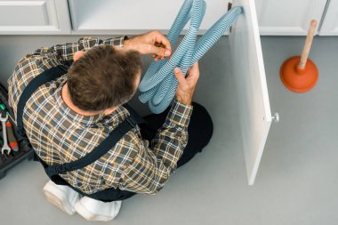 Tesisatçı mutfakta lavabonun boru tutarak yüksek açılı görünüş