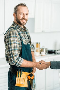 yakışıklı tesisatçı ve mutfakta tokalaşırken müşteri gülümseyen