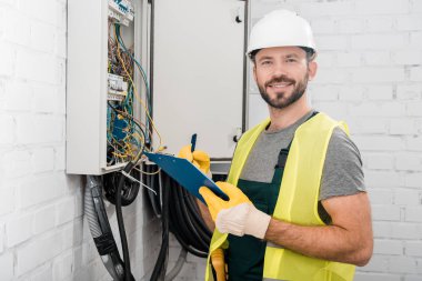 yakışıklı elektrikçi holding Pano elektrik kutusu koridor ve kameraya arıyor yakınındaki gülümseyen