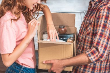 cropped image of couple unpacking utensil from cardboard box at new home clipart