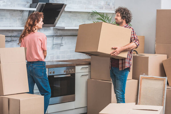 couple unpacking cardboard boxes together at new kitchen