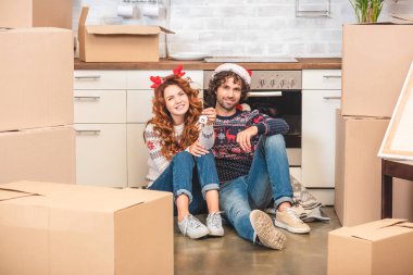 tuşu tutmakta ve Noel yeni apartman dairesinde otururken kameraya gülümseyen mutlu genç çift