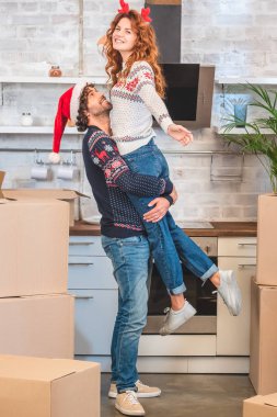 mutlu genç çift yeni evinde Noel yerini değiştirme sırasında sarılma   