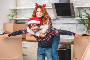 eğleniyor ve Noel yerini değiştirme sırasında kameraya gülümseyen mutlu genç çift  