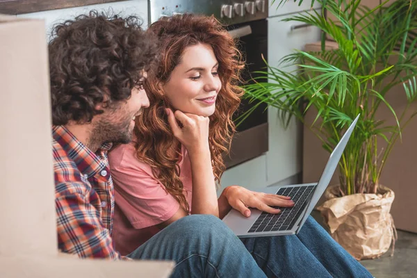 Side View Cheerful Couple Sitting Laptop Cardboard Boxes Floor New — Stock Photo, Image