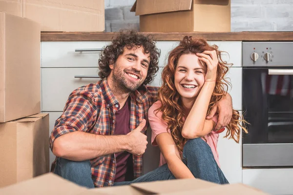 Happy Couple Sitting Floor Cardboard Boxes New Kitchen Boyfriend Showing — Stock Photo, Image