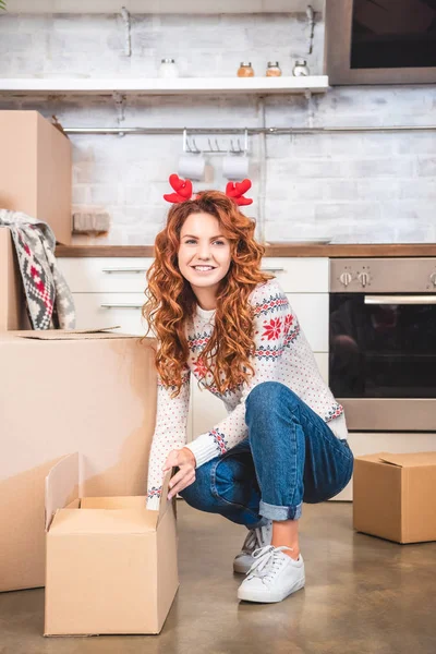 Happy Young Woman Antlers Headband Unpacking Cardboard Boxes Smiling Camera — Free Stock Photo