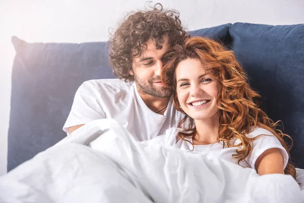 Feliz Jovem Casal Rindo Enquanto Deitado Juntos Cama — Fotografia de Stock