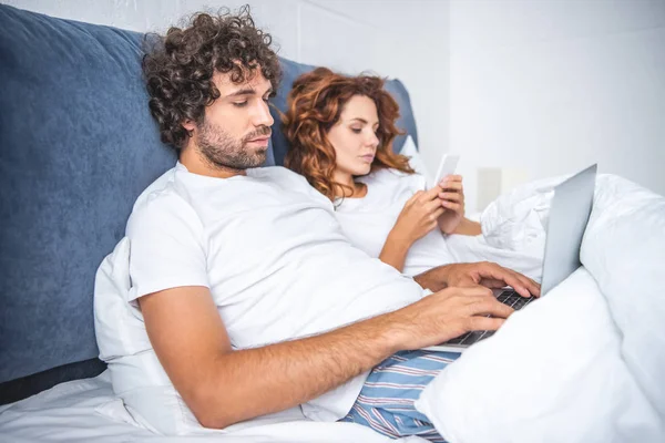 Jovem Casal Usando Laptop Smartphone Enquanto Deitado Cama Cama — Fotos gratuitas