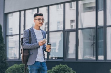 Asya adam kahve ile gri ceketli Smartphone sokakta kullanmaya devam
