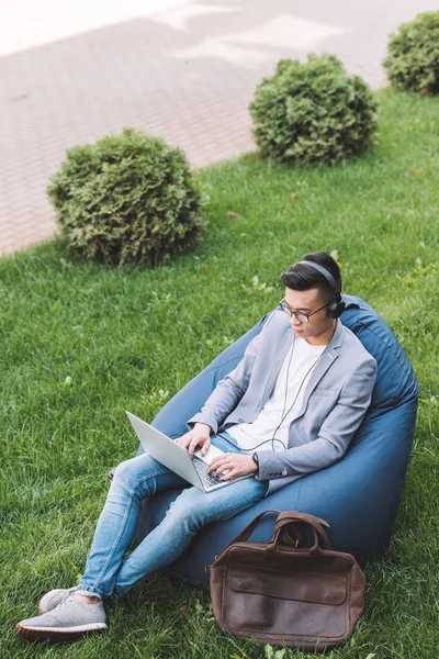 Asian Freelancer Working Laptop While Sitting Bean Bag Chair Lawn — Free Stock Photo