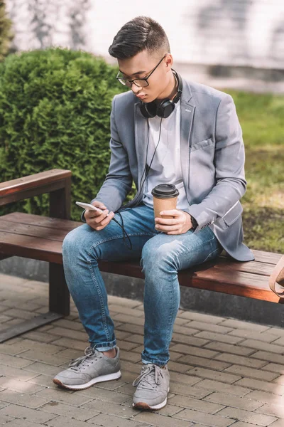 Elegante Asiático Homem Com Café Para Smartphone Fones Ouvido Sentado — Fotografia de Stock Grátis