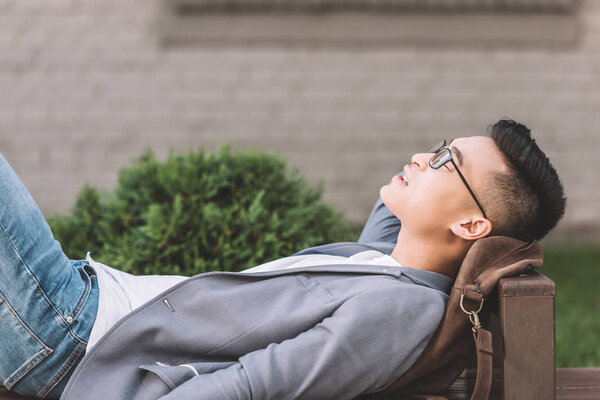 stylish asian man sleeping on bench