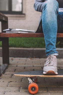 kısmi kaykay ve ders kitapları ile bankta oturan adam görünümünü