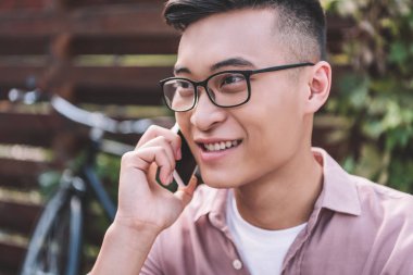 konuşmak smartphone üzerinde gözlük gülümseyen Asyalı adam