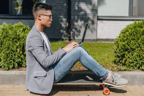 Side View Asian Freelancer Using Laptop While Sitting Longboard Street — Free Stock Photo