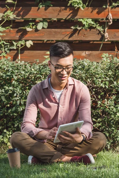 Молодий Азіатський Чоловік Використовує Цифровий Планшет Зеленій Траві Парку — Безкоштовне стокове фото
