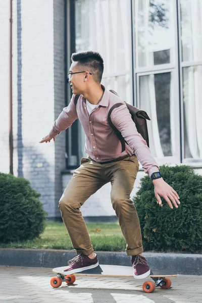 Ung Asiatisk Man Med Ryggsäck Ridning Longboard Gatan — Gratis stockfoto