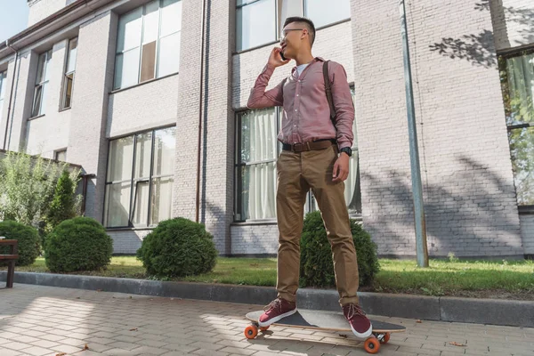 Asian Man Talking Smartphone While Standing Longboard Street — Free Stock Photo