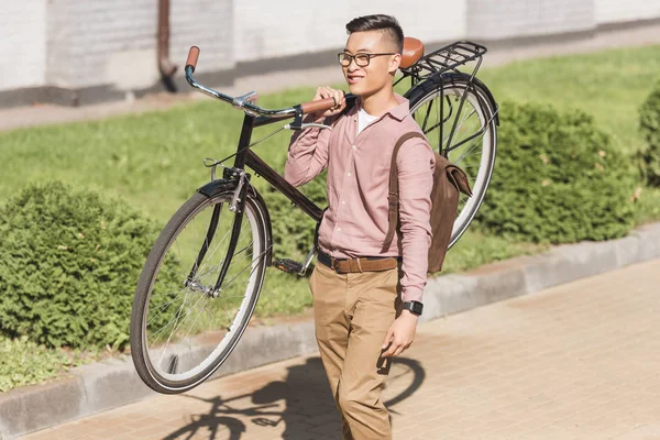 Sonriente Joven Asiático Hombre Llevar Bicicleta Mientras Caminar Calle — Foto de stock gratis