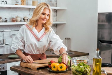 Sarışın yetişkin kadın evde akşam yemeği için salata hazırlık