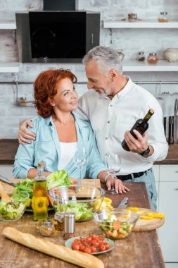 mutfak ve onlar birbirine bakarak akşam yemeği için salata hazırlık sırasında sarılma karısı kocası