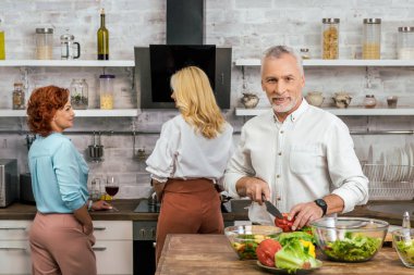 yakışıklı adam salata yemek için evde, kadınlar şarap ile konuşmaya hazırlanıyor.