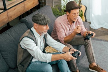 olgun erkek arkadaş kanepede oturan ve joystick ile oynarken yüksek açılı görünüş