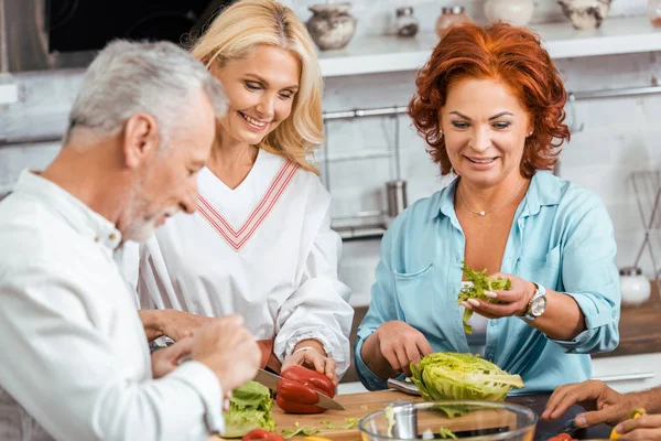 微笑成熟的朋友准备健康排毒沙拉在家里吃饭 — 图库照片