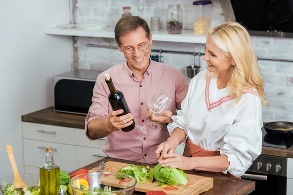 Beautiful Wife Preparing Salad Dinner Home Smiling Husband Holding Wine — Free Stock Photo