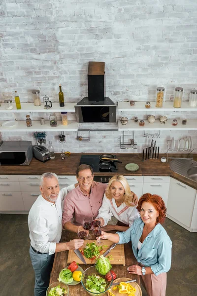 High Angle View Old Friends Clinking Wineglasses Kitchen Looking Camera — Free Stock Photo
