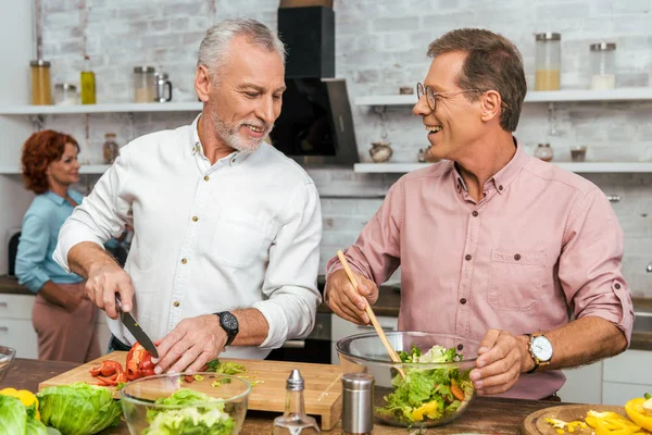 Homens Sorridentes Bonitos Preparando Salada Para Jantar Casa — Fotografia de Stock