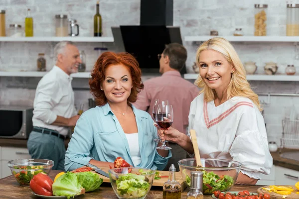 Mujeres Hermosas Sonrientes Preparando Ensalada Para Cena Sosteniendo Gafas Vino — Foto de Stock