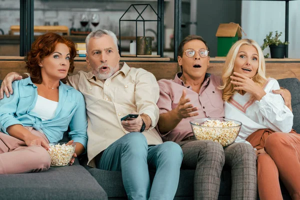 Σοκαρισμένος Ώριμοι Φίλοι Που Κάθεται Στον Καναπέ Και Βλέποντας Τηλεόραση — Δωρεάν Φωτογραφία