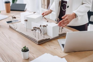 partial view of professional architect working with house model at workplace clipart