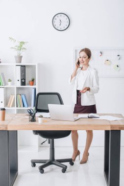başarılı işkadını modern ofis dizüstü bilgisayar ile Smartphone cep telefonu ile konuşmak
