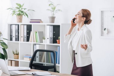 smartphone işyeri dizüstü bilgisayar ile konuşurken işkadını gülüyor