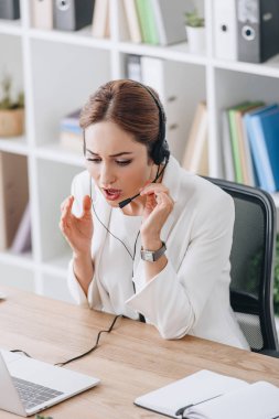 endişeli operatör kulaklık ve modern ofis içinde laptop ile çalışma