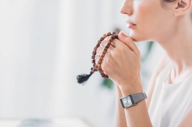 cropped view of woman praying with wooden rosary beads clipart